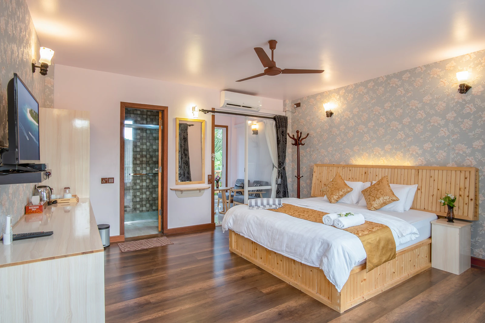 Wide room overview from the entrance with bed, television, and balcony