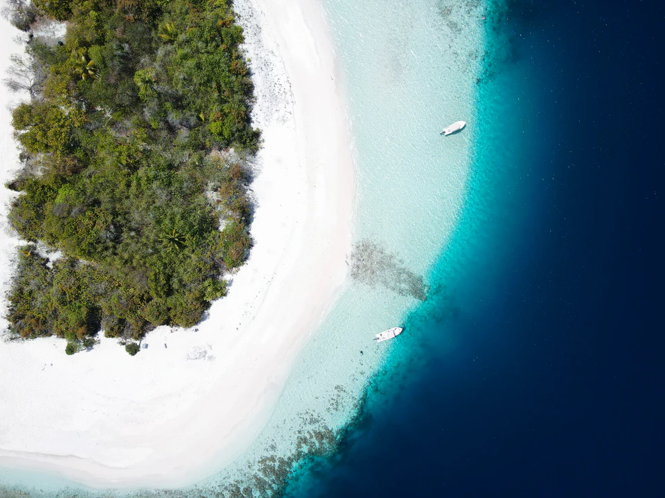 Top-down aerial view of an island beach with a small boat offshore