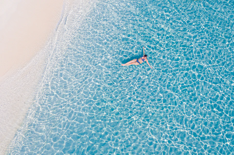 Closer top-down view of two swimmers beside the sand edge