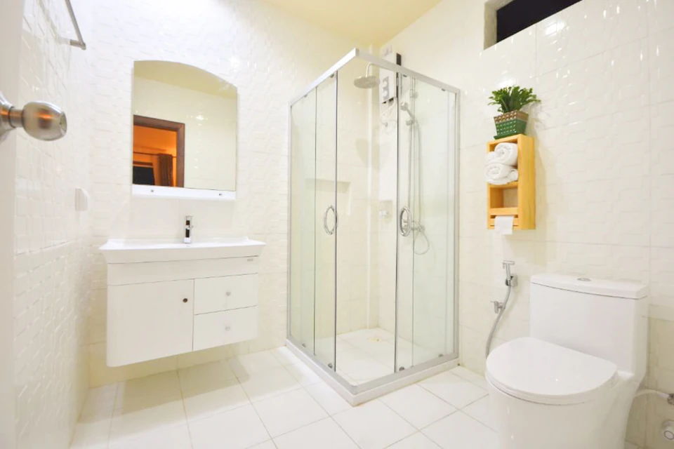 Bright guest bathroom with glass shower, vanity, and toilet