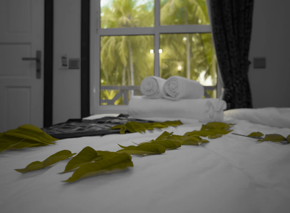 Close-up of decorative leaves and rolled towels on a bed