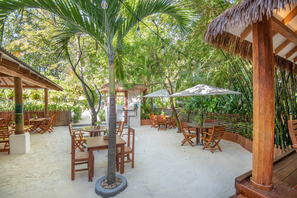 Sandy outdoor dining courtyard with tables and umbrellas