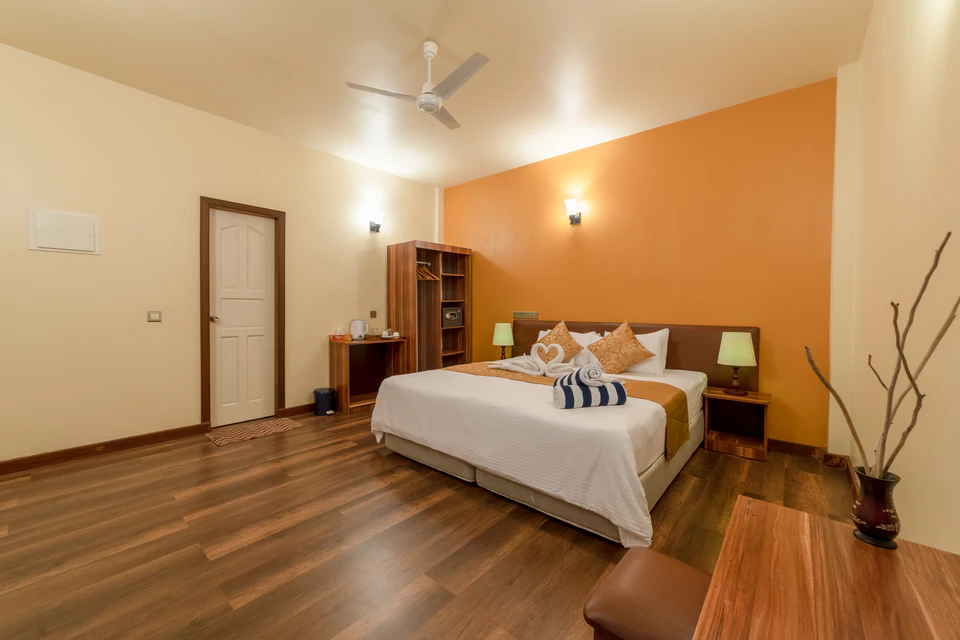 Wide double-bed room view with orange accent wall and entrance