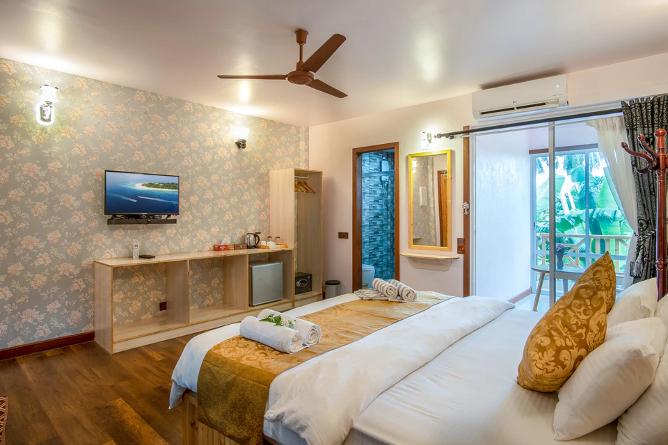 View across the double bed toward the television and balcony