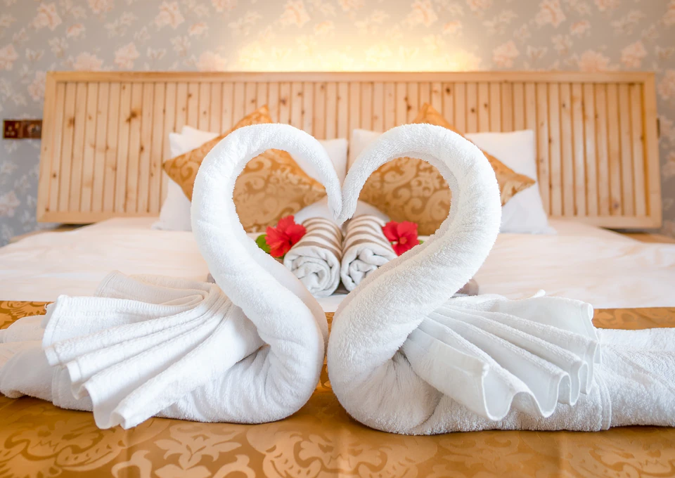 Closer view of towel swans and flower petals on the bed